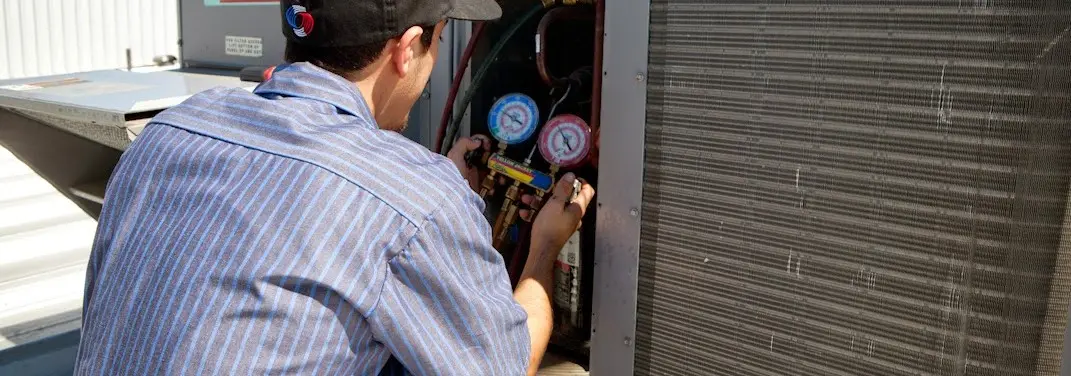 HVAC technician servicing a condenser unit in Ansonia